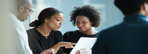 A picture containing men and women at a business meeting