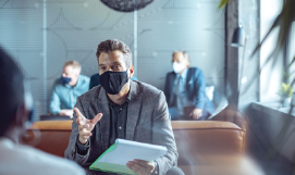 A picture of a business 
                           man wearing a mask in a meeting