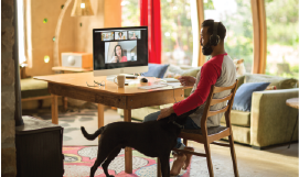 A picture containing a man 
                           in his home office with a dog