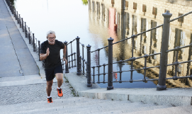 A picture containing a man running outside up steps
